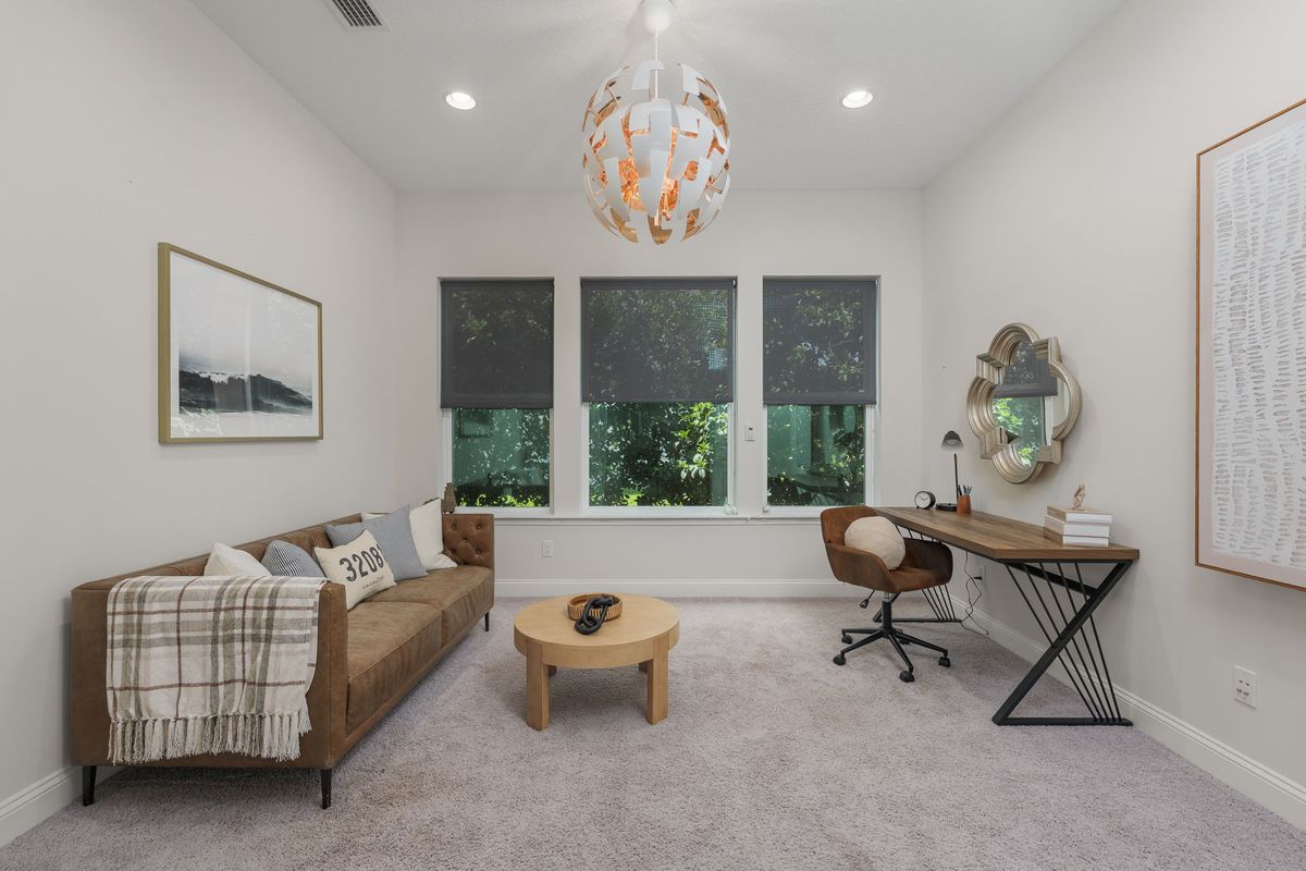 Study with a leather sofa, a round wood coffee table, a writing desk and a woven pendant light